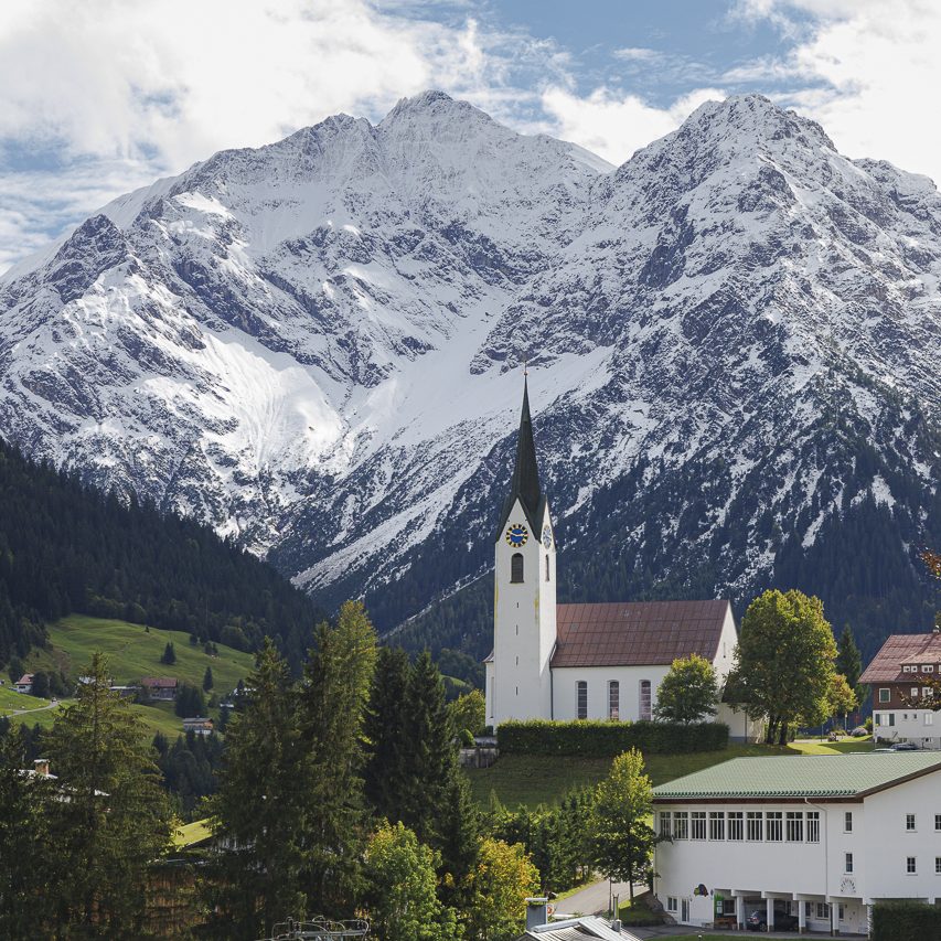 Landschaft im Walistal. Alpenlandschaft mit schneebedeckten Bergen und einer Kirche im Vordergrund.