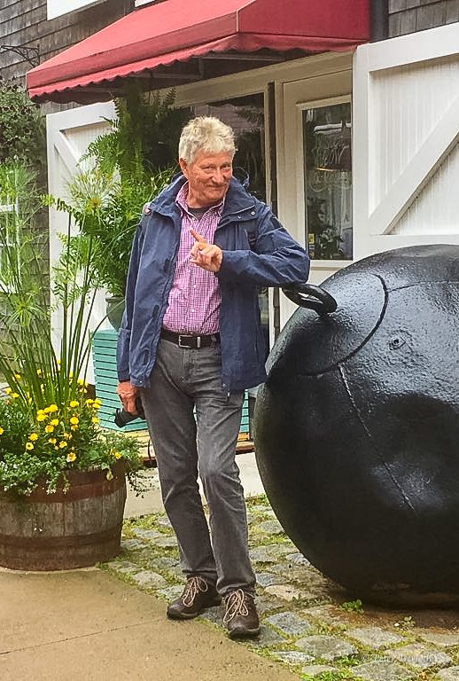Peter Iserloth - Autor dieser Website. Ein Mann - Peter Iserloth - in einem blauen Jackett steht neben einem großen schwarzen Objekt im Freien.