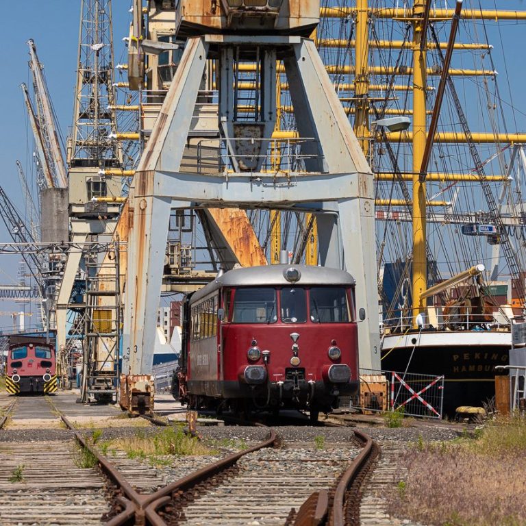 Fotografie eines Schienenbusses im Museumshafen Schuppen 50 in Hamburg, im Hintergrund Hafenkrane und die "Peking"