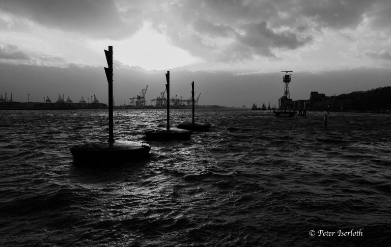 Fotografie eines Leitdamms im Hamburger Hafen, mit Wegzeigesymbole.